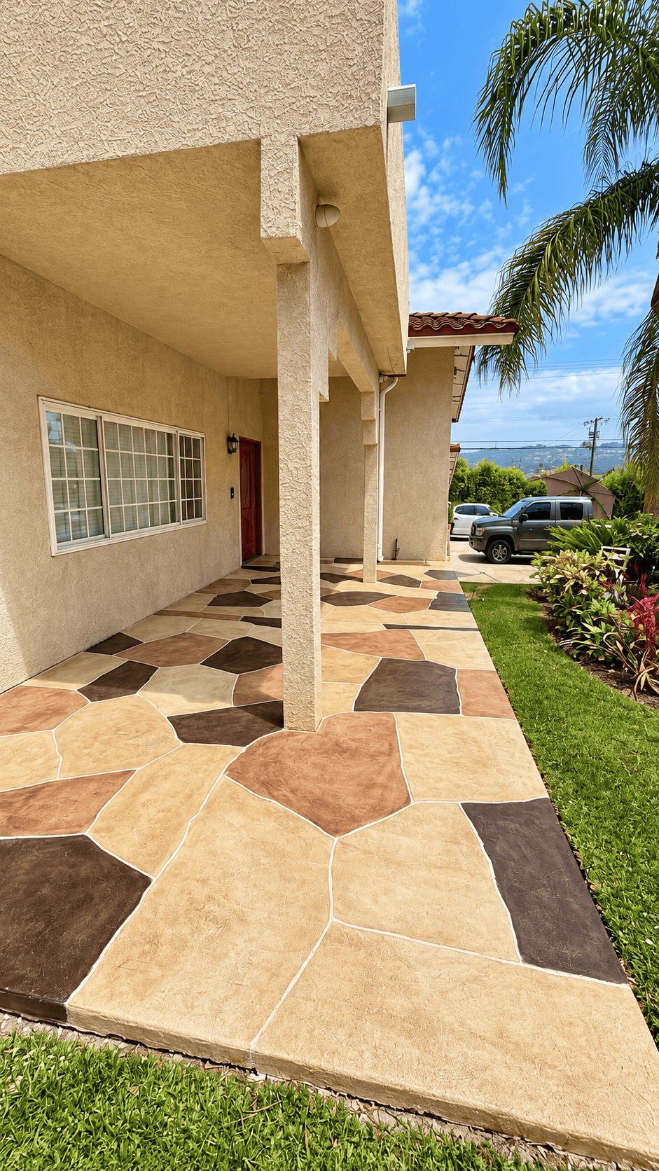 Colorful patterned outdoor flooring with house and palm trees in background.