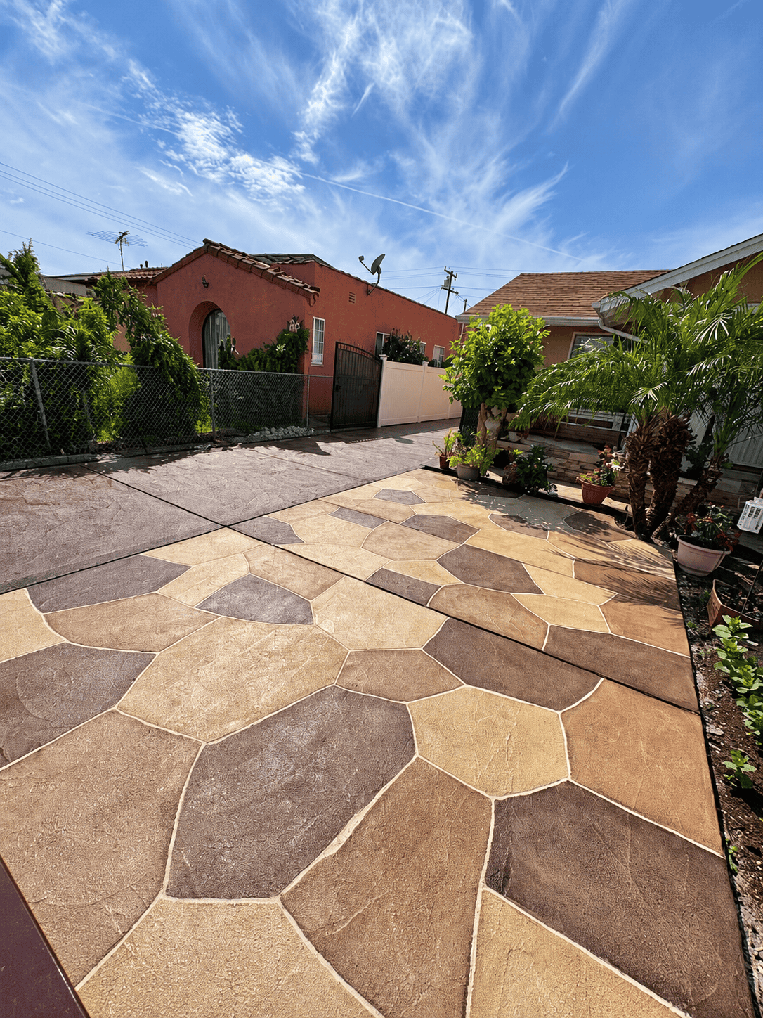 Beautiful stone paver patio in a residential backyard with plants and clear sky.