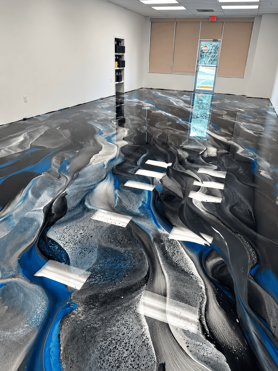 Contemporary epoxy flooring with swirling black, white, and blue patterns in a commercial space.