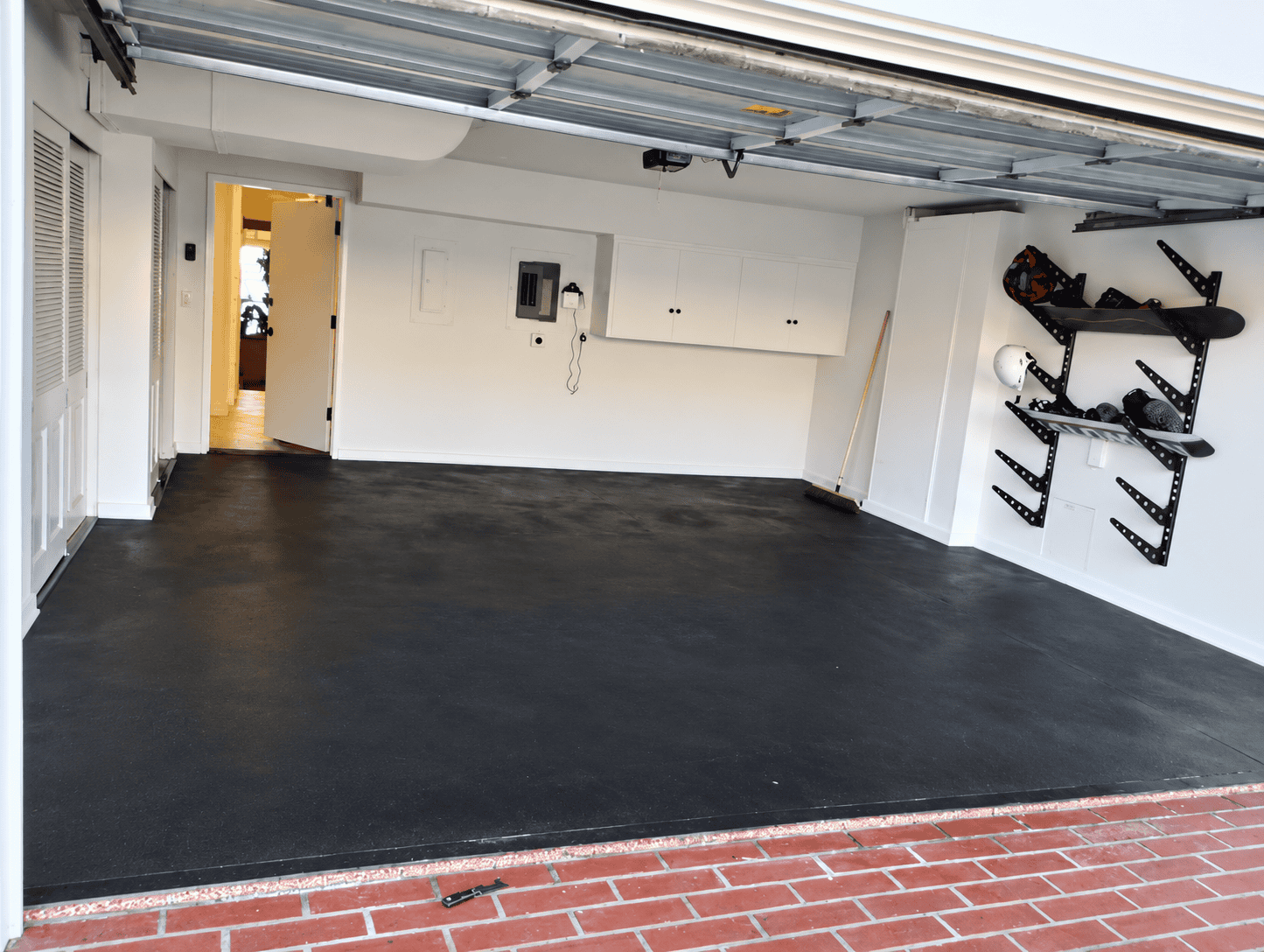 Freshly coated black epoxy garage floor with organized storage shelves.